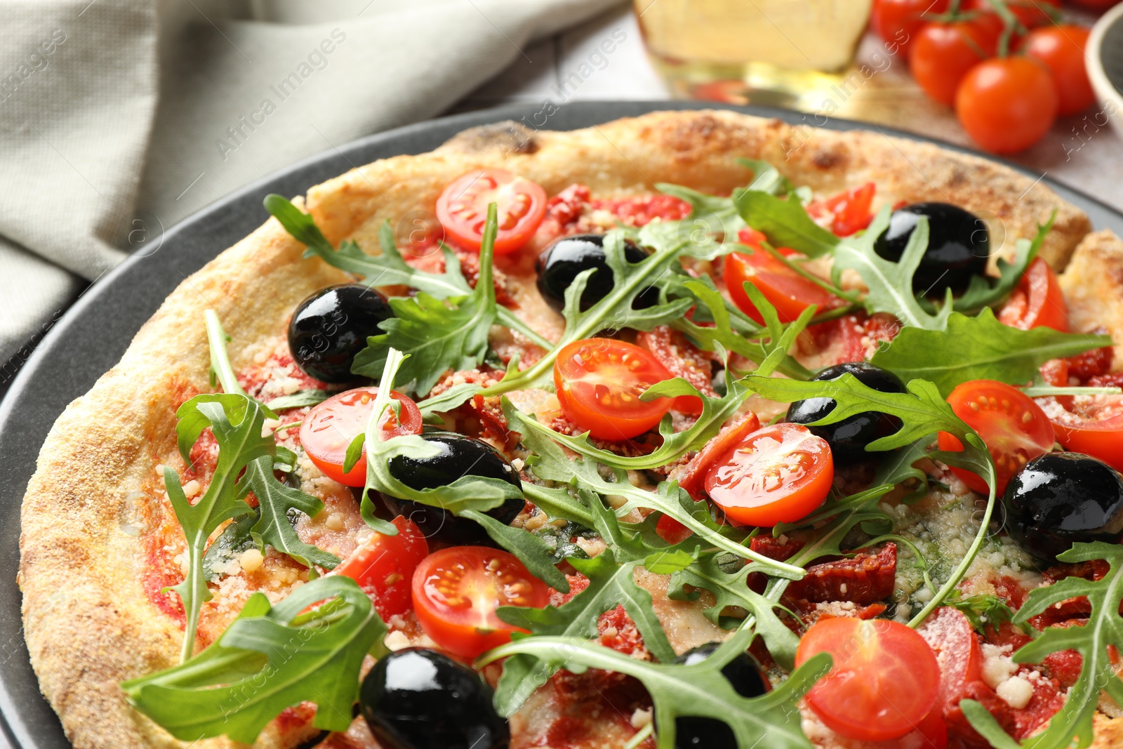 Photo of Tasty pizza with tomatoes, olives and arugula on table, closeup