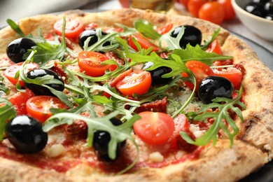 Tasty pizza with tomatoes, olives and arugula on table, closeup