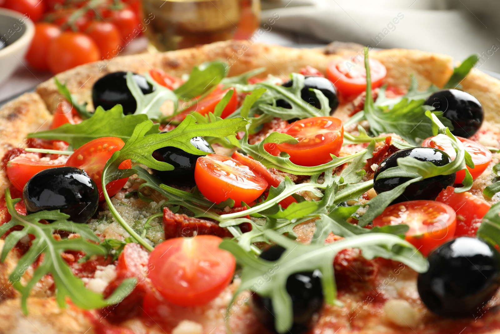 Photo of Tasty pizza with tomatoes, olives and arugula on table, closeup