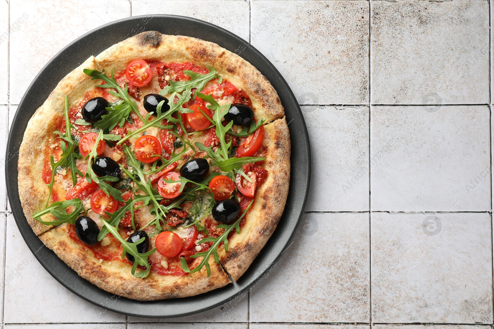 Photo of Tasty pizza with olives and arugula on light tiled table, top view. Space for text