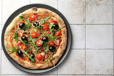 Tasty pizza with olives and arugula on light tiled table, top view. Space for text