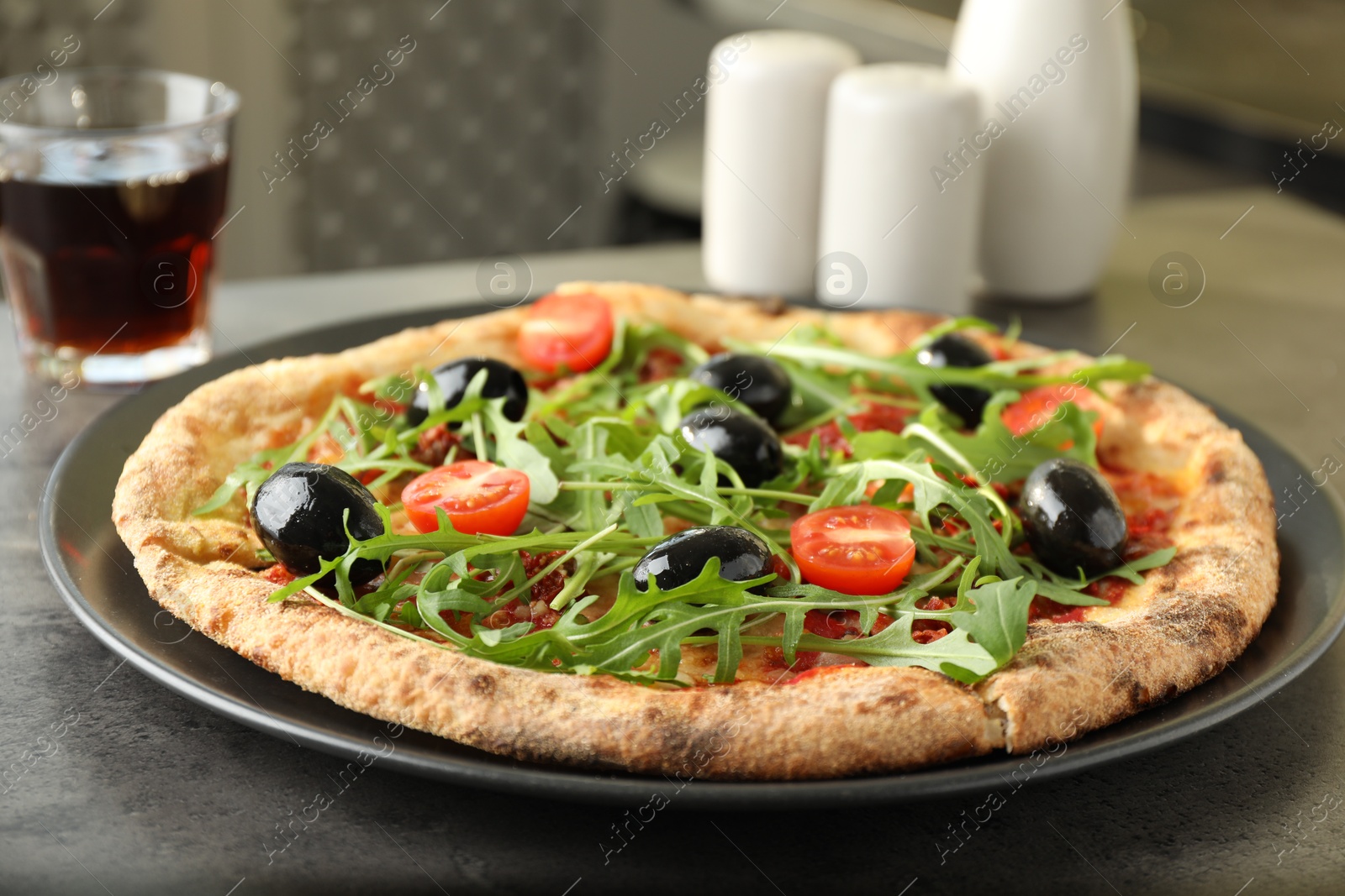 Photo of Delicious pizza with olives, cherry tomatoes, arugula and soda drink on grey table indoors, closeup