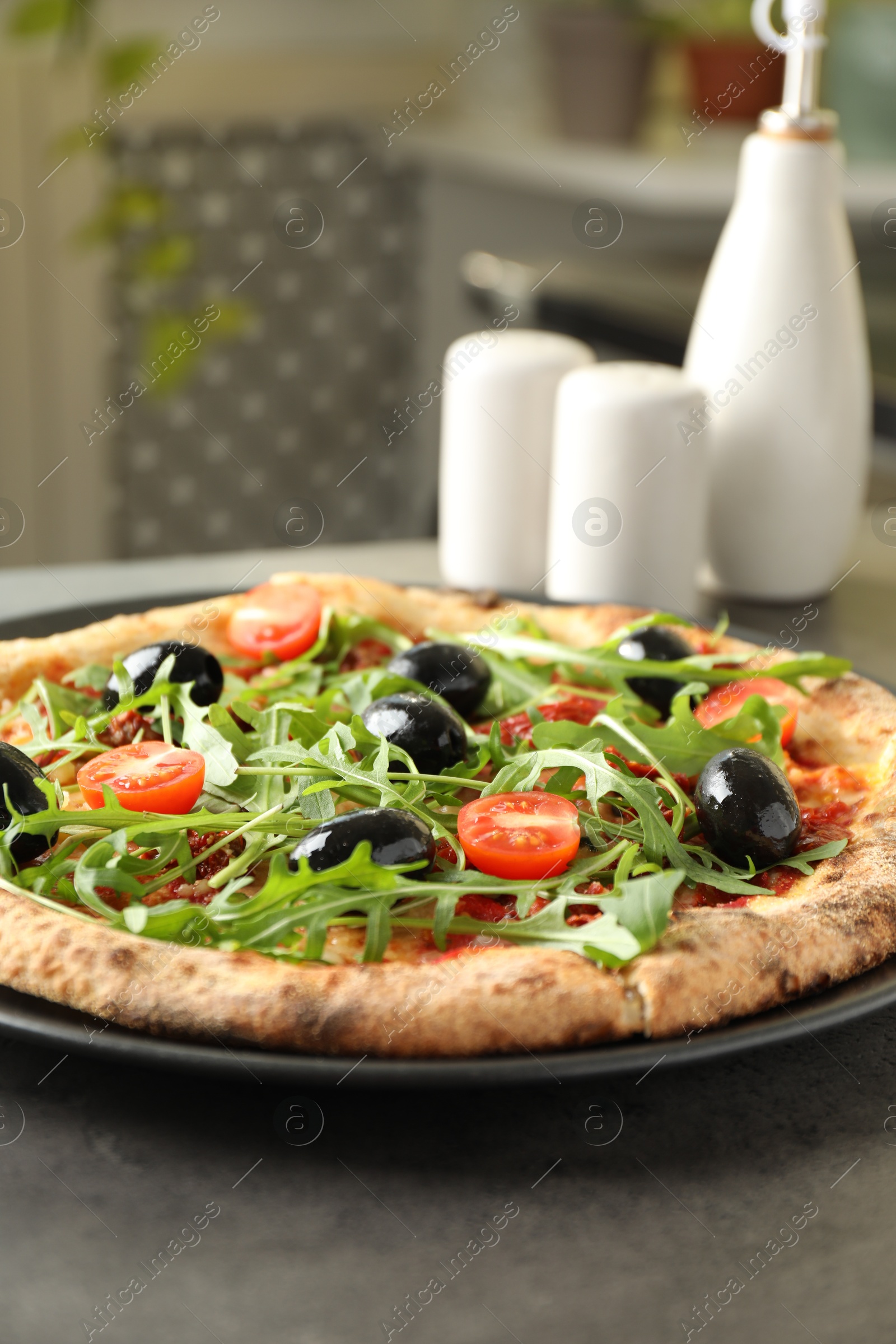 Photo of Delicious pizza with olives, cherry tomatoes and arugula on grey table indoors, closeup