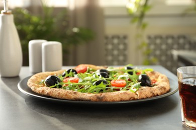 Delicious pizza with olives, cherry tomatoes, arugula and soda drink on grey table indoors, closeup