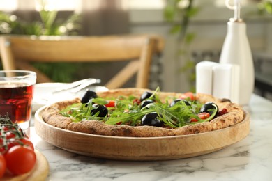 Delicious pizza with olives, cherry tomatoes, arugula and soda drink on white marble table indoors, closeup