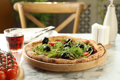 Delicious pizza with olives, cherry tomatoes, arugula and soda drink on white marble table indoors, closeup