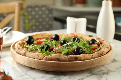 Delicious pizza with olives, cherry tomatoes and arugula on white marble table indoors, closeup