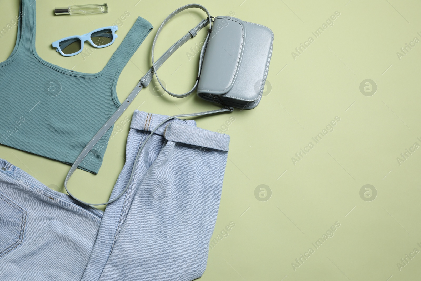 Photo of Stylish women's clothes and different accessories on light olive background, flat lay. Space for text