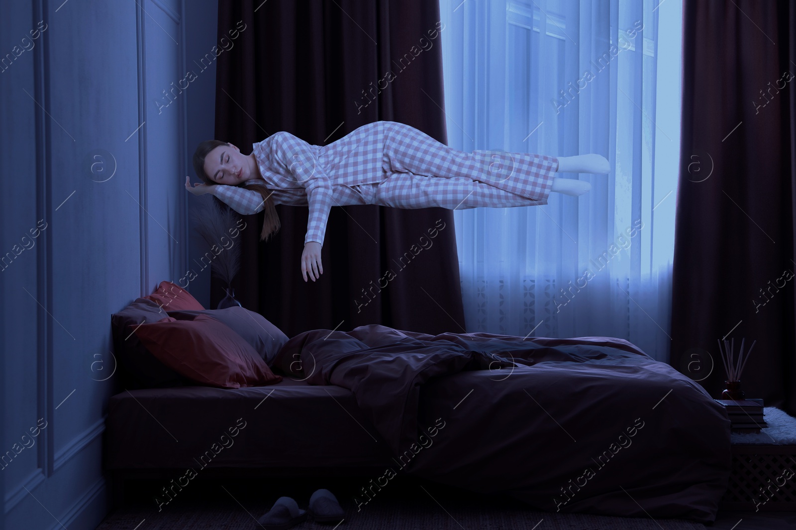 Image of Sleepwalking. Young woman floating above bed at home