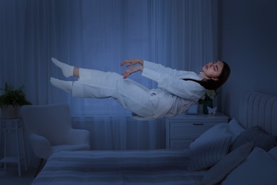 Image of Sleepwalking. Young woman floating above bed at home, toned in blue