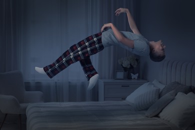 Image of Sleepwalking. Young man floating over bed at home, toned in blue