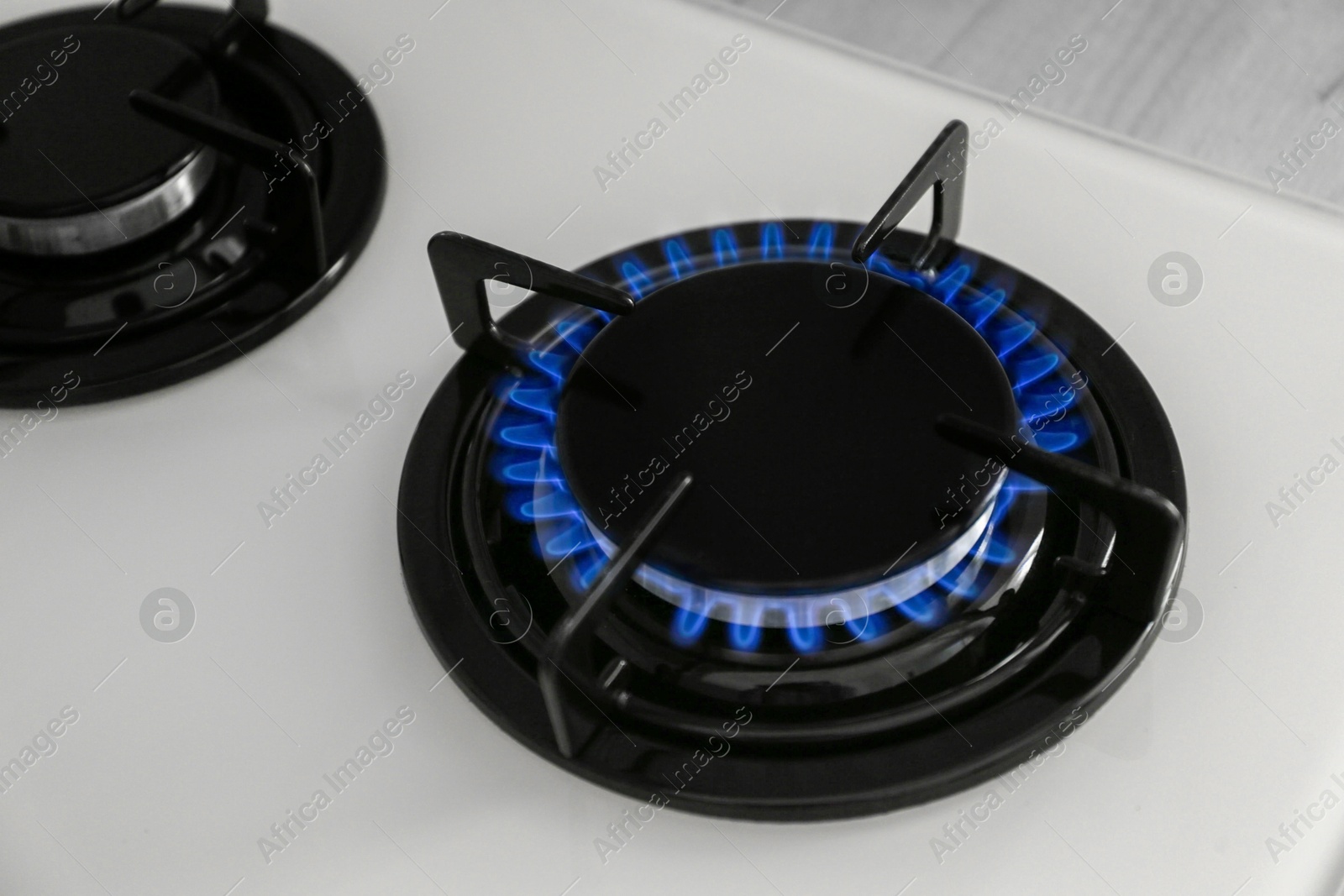 Photo of Gas burner of modern stove with burning blue flame, closeup