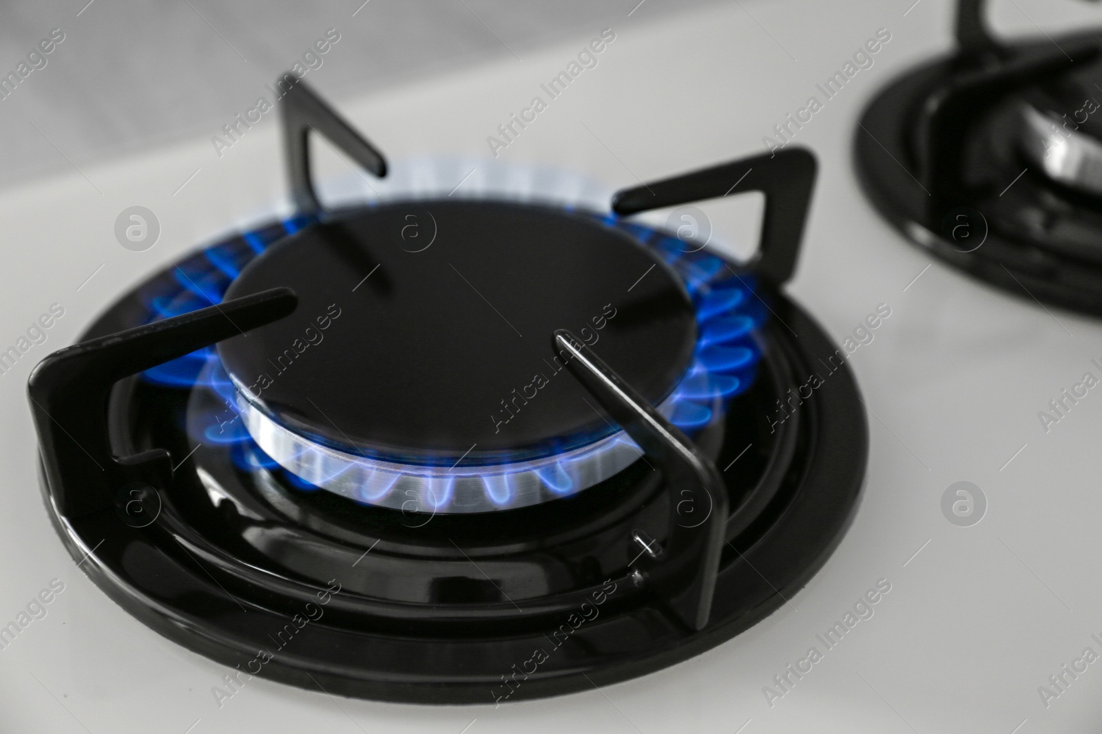 Photo of Gas burner of modern stove with burning blue flame, closeup