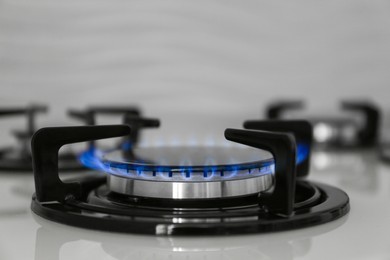 Photo of Gas burner of modern stove with burning blue flame, closeup