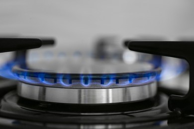 Photo of Gas burner of modern stove with burning blue flame, closeup