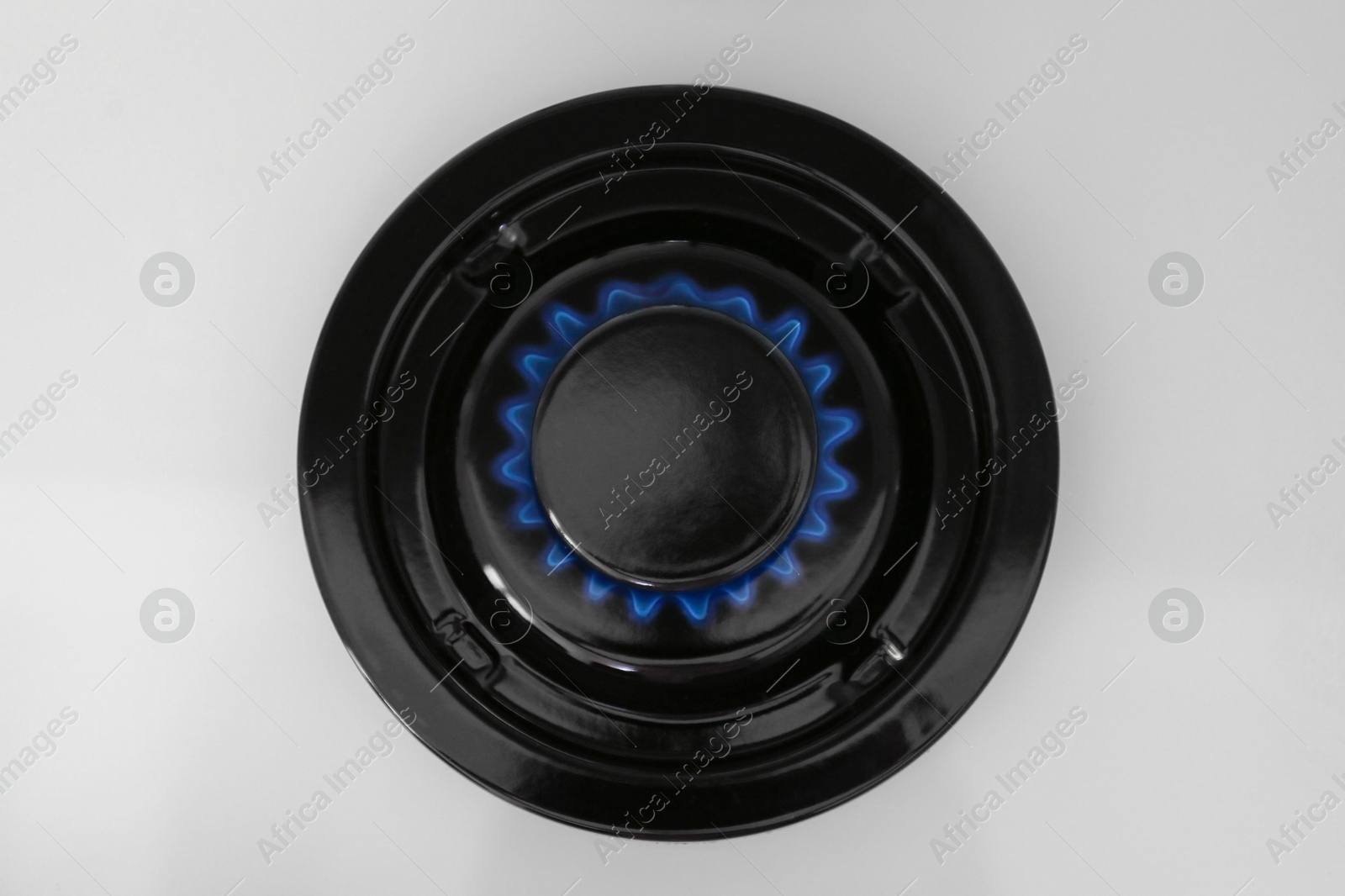 Photo of Gas burner of modern stove with burning blue flame, top view