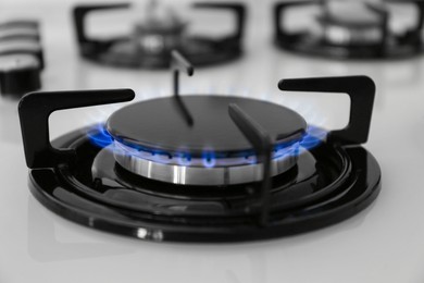 Photo of Gas burner of modern stove with burning blue flame, closeup