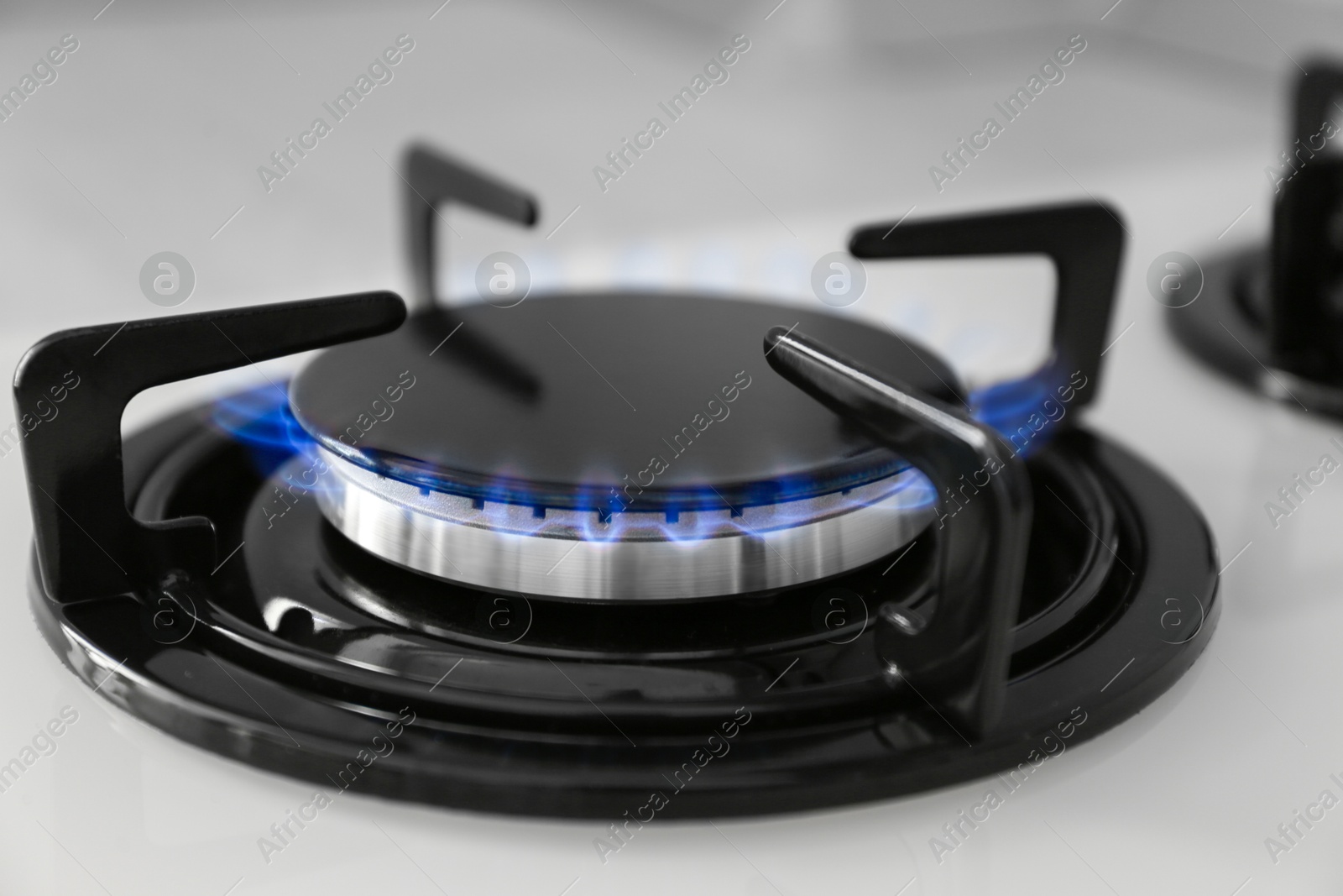 Photo of Gas burner of modern stove with burning blue flame, closeup