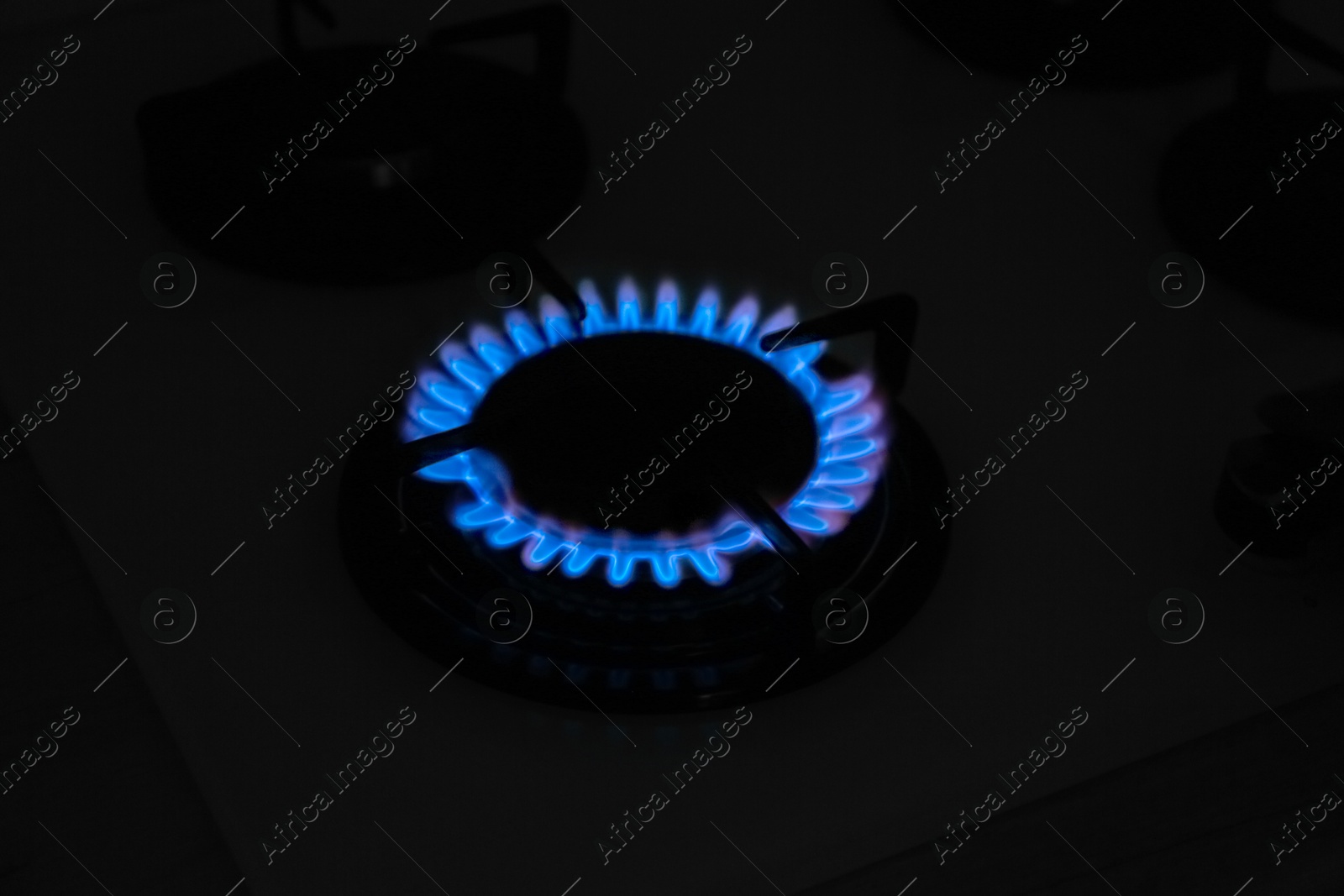 Photo of Gas burner of modern stove with burning blue flame at night