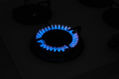 Photo of Gas burner of modern stove with burning blue flame at night