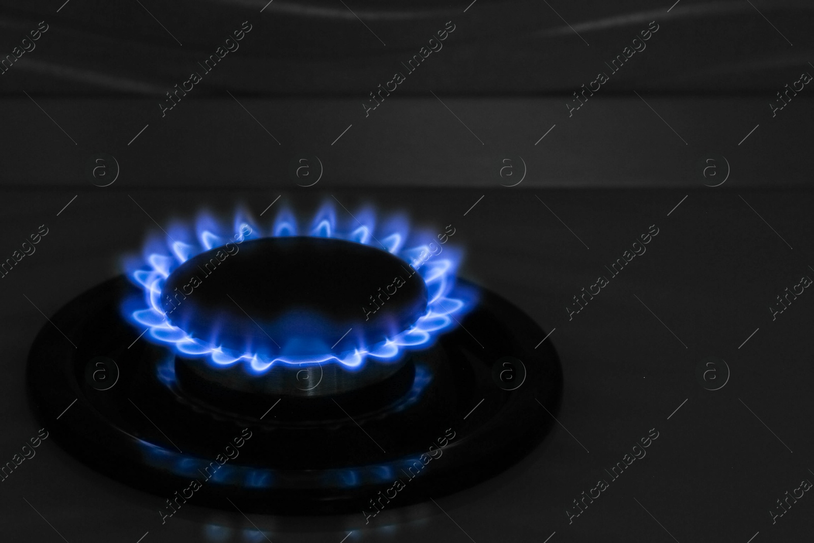 Photo of Gas burner of modern stove with burning blue flame at night