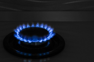 Photo of Gas burner of modern stove with burning blue flame at night