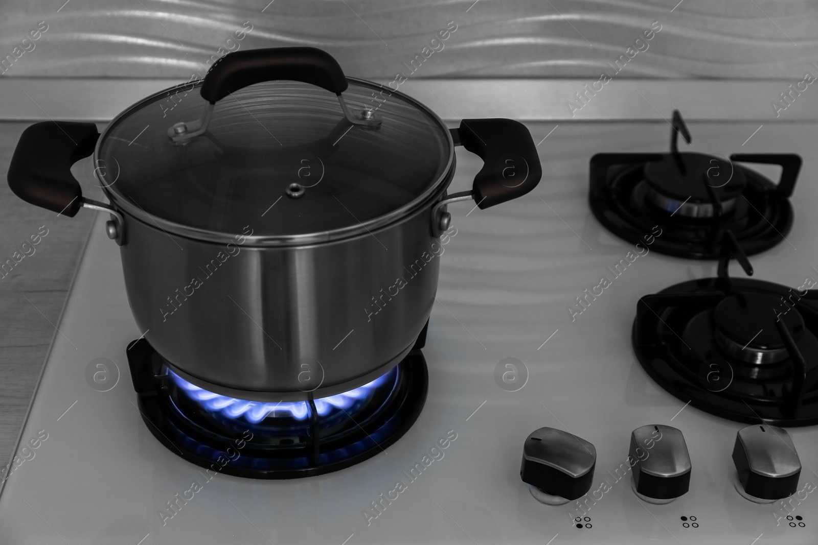 Photo of Pot on modern gas cooktop in kitchen