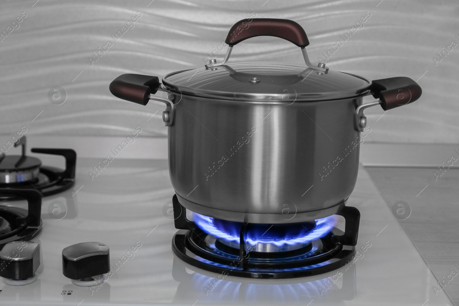 Photo of Pot on modern gas cooktop in kitchen