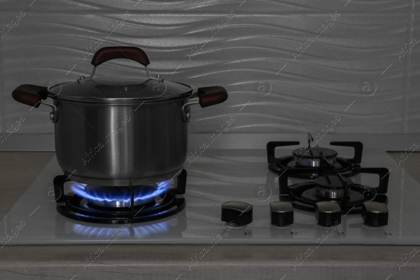 Photo of Pot on modern gas cooktop in kitchen