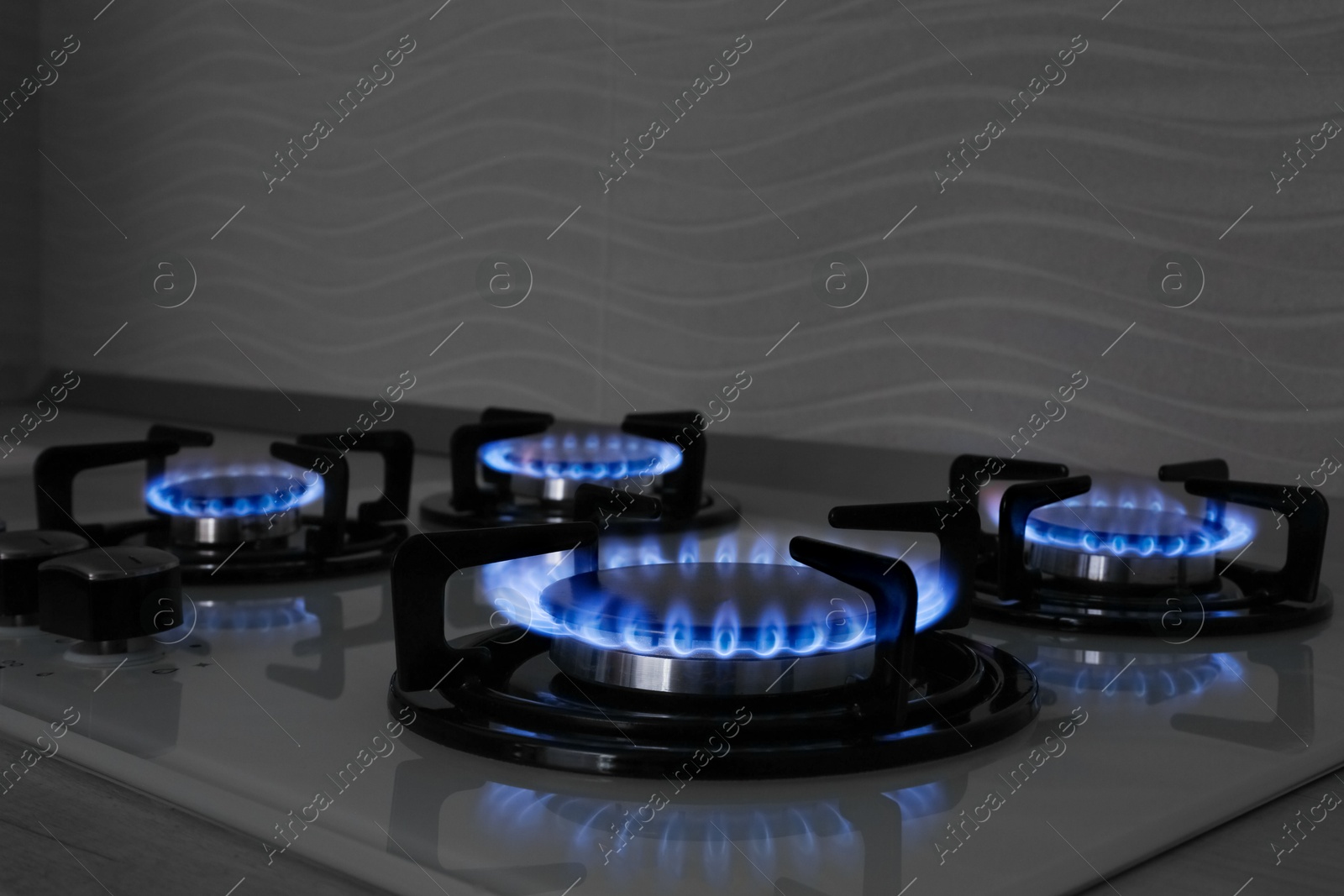 Photo of Modern gas cooktop with burning blue flames in kitchen