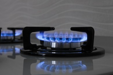 Photo of Modern gas cooktop with burning blue flames in kitchen