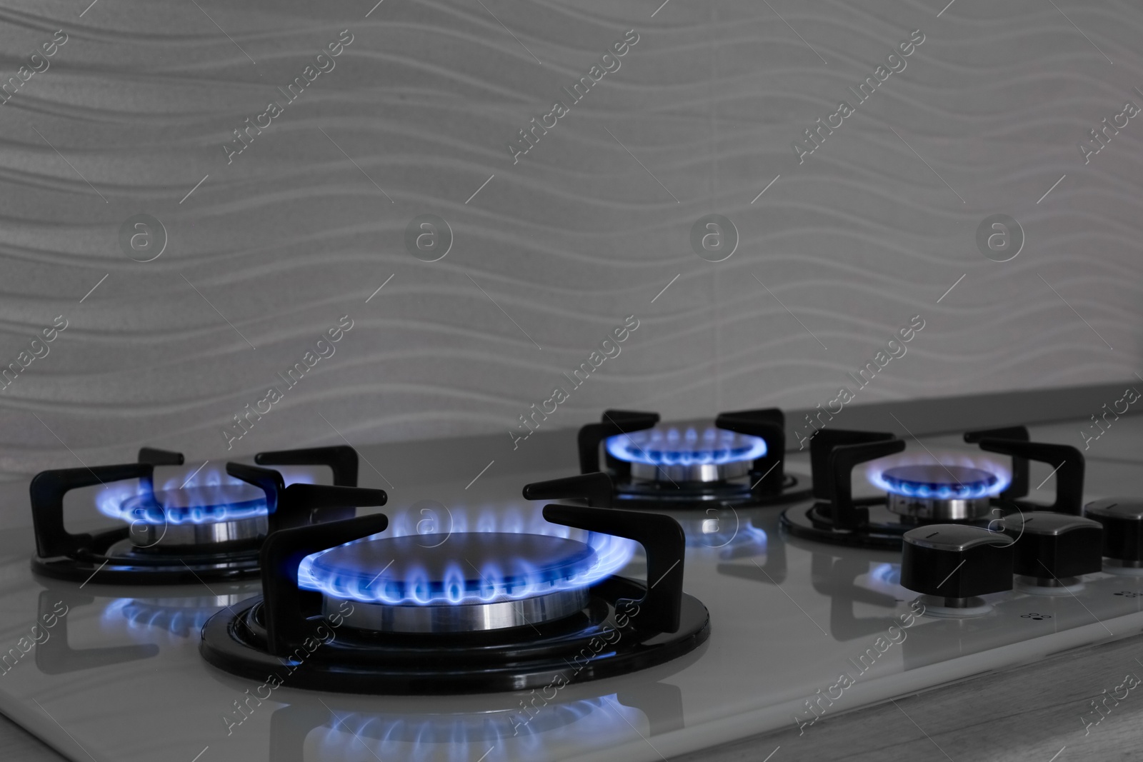 Photo of Modern gas cooktop with burning blue flames in kitchen