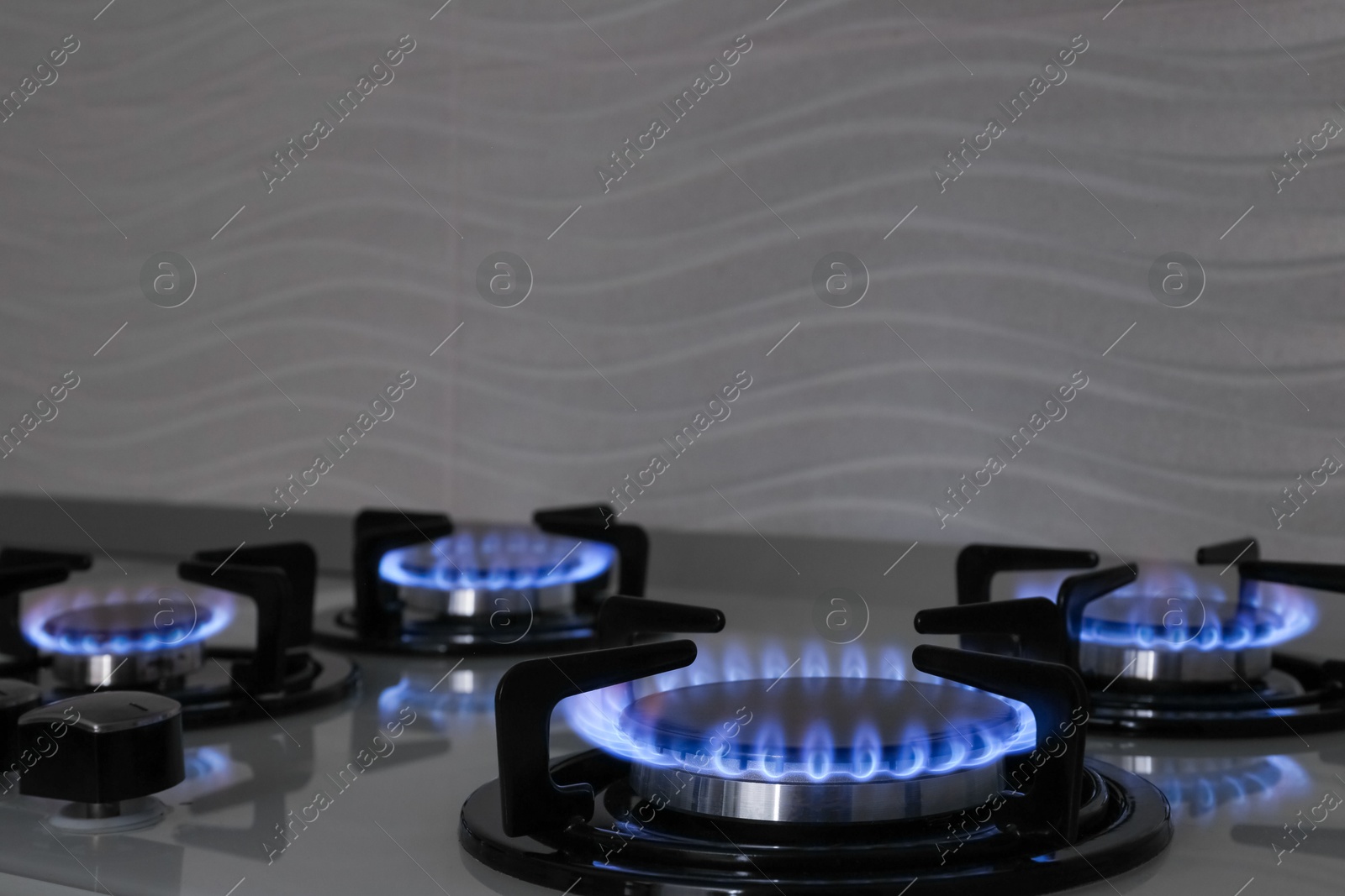 Photo of Modern gas cooktop with burning blue flames in kitchen