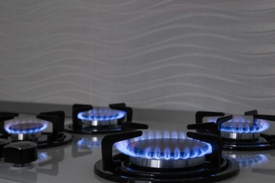 Photo of Modern gas cooktop with burning blue flames in kitchen