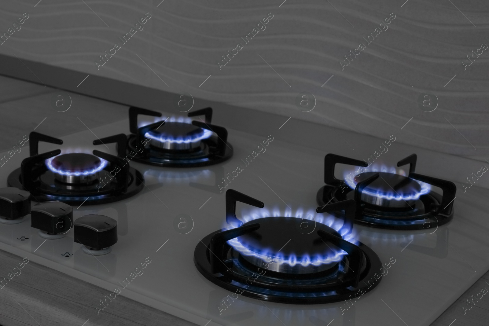 Photo of Modern gas cooktop with burning blue flames in kitchen