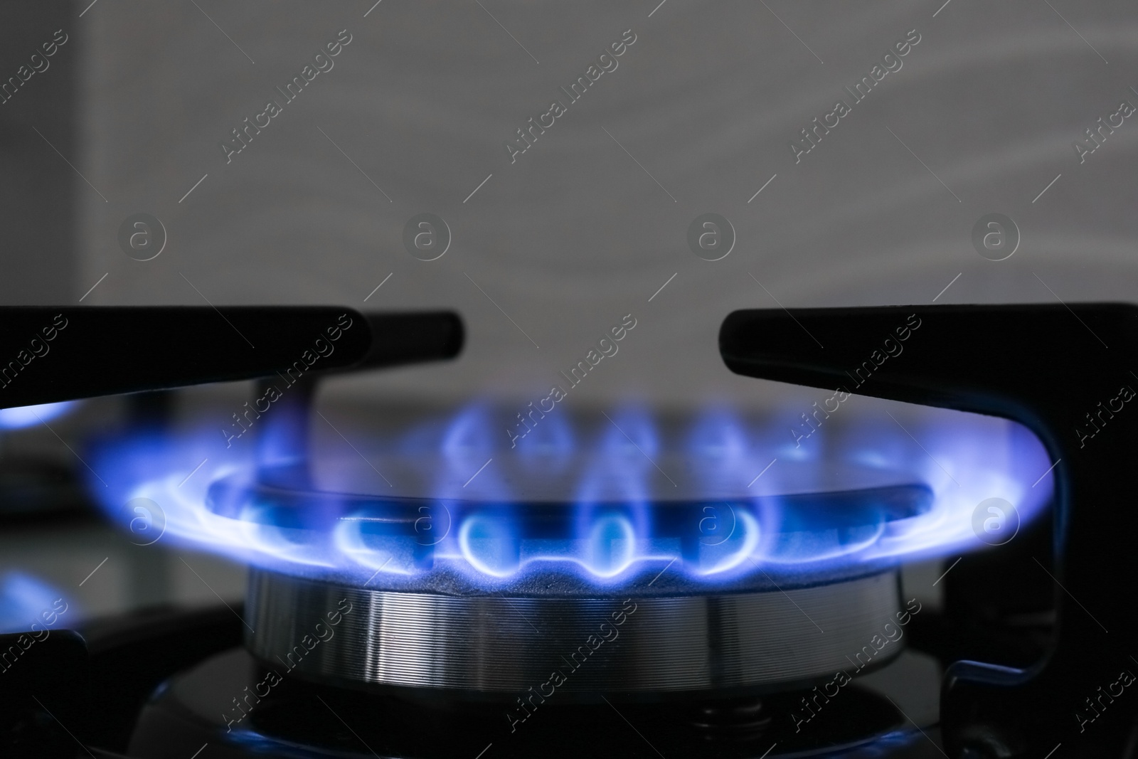 Photo of Gas burner of modern stove with burning blue flame, closeup