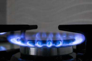 Photo of Gas burner of modern stove with burning blue flame, closeup