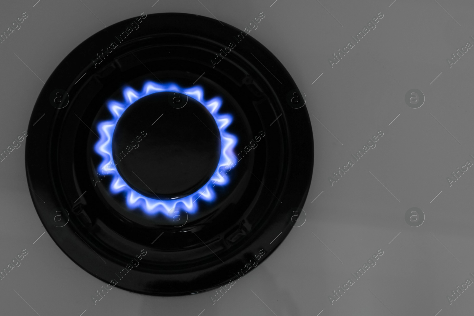 Photo of Gas burner of modern stove with burning blue flame, top view