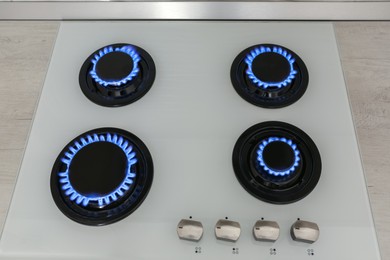 Photo of Modern gas cooktop with burning blue flames in kitchen