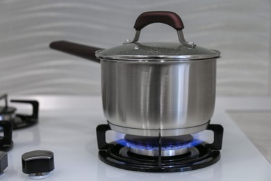 Photo of Pot on modern kitchen stove with burning gas