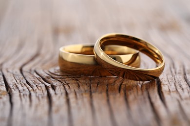 Photo of Beautiful golden wedding rings on wooden background, closeup