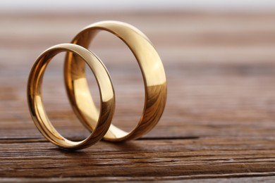 Photo of Beautiful golden wedding rings on wooden background, closeup