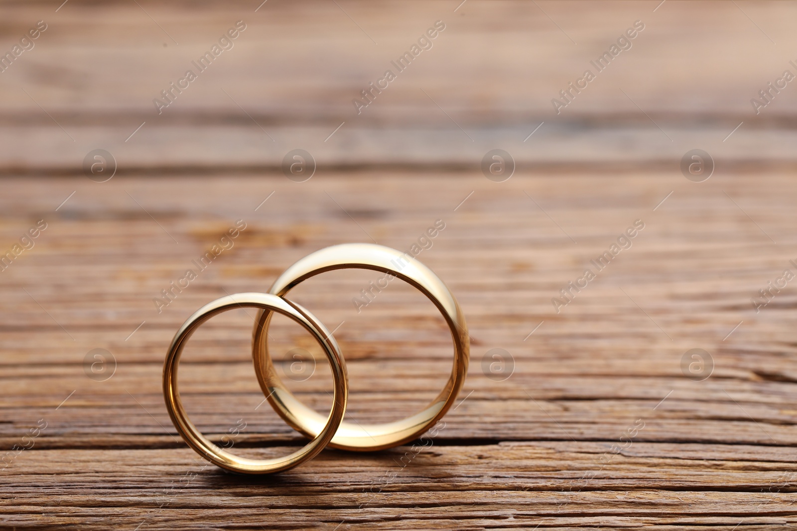 Photo of Beautiful golden wedding rings on wooden background