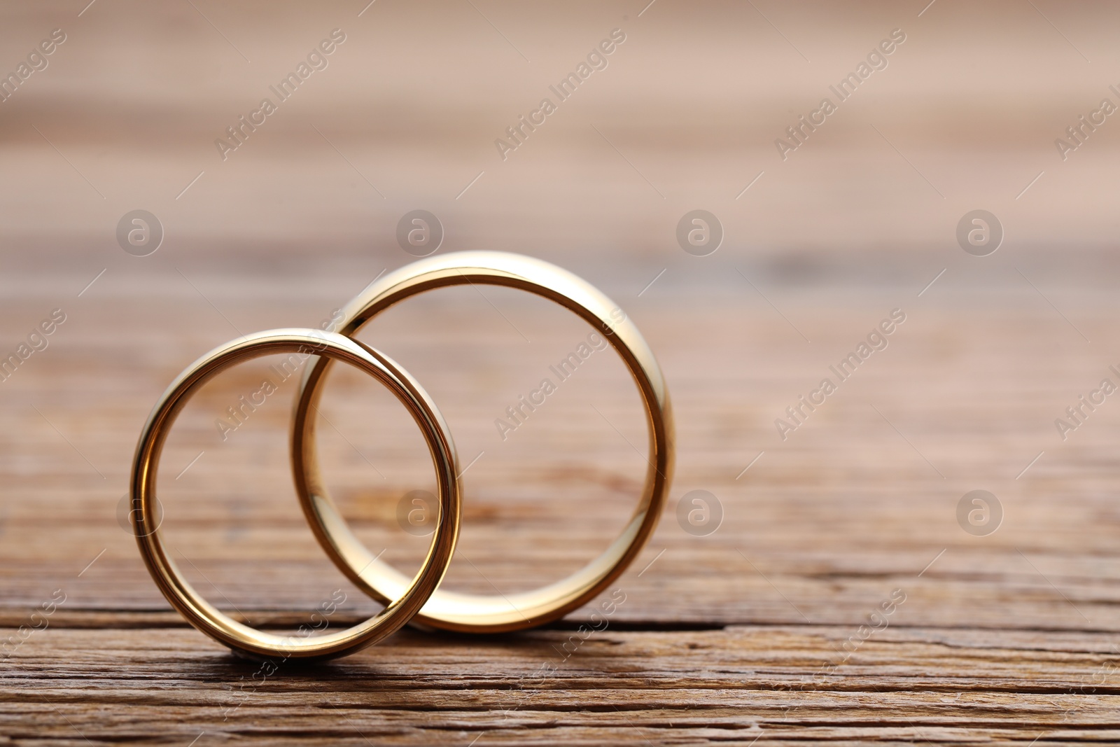 Photo of Beautiful golden wedding rings on wooden background