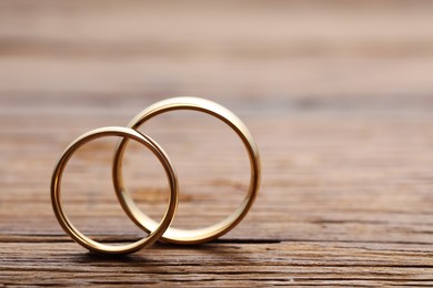 Photo of Beautiful golden wedding rings on wooden background