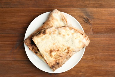 Photo of Halves of tasty calzone on wooden table, top view