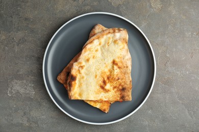 Photo of Halves of tasty calzone on grey textured table, top view