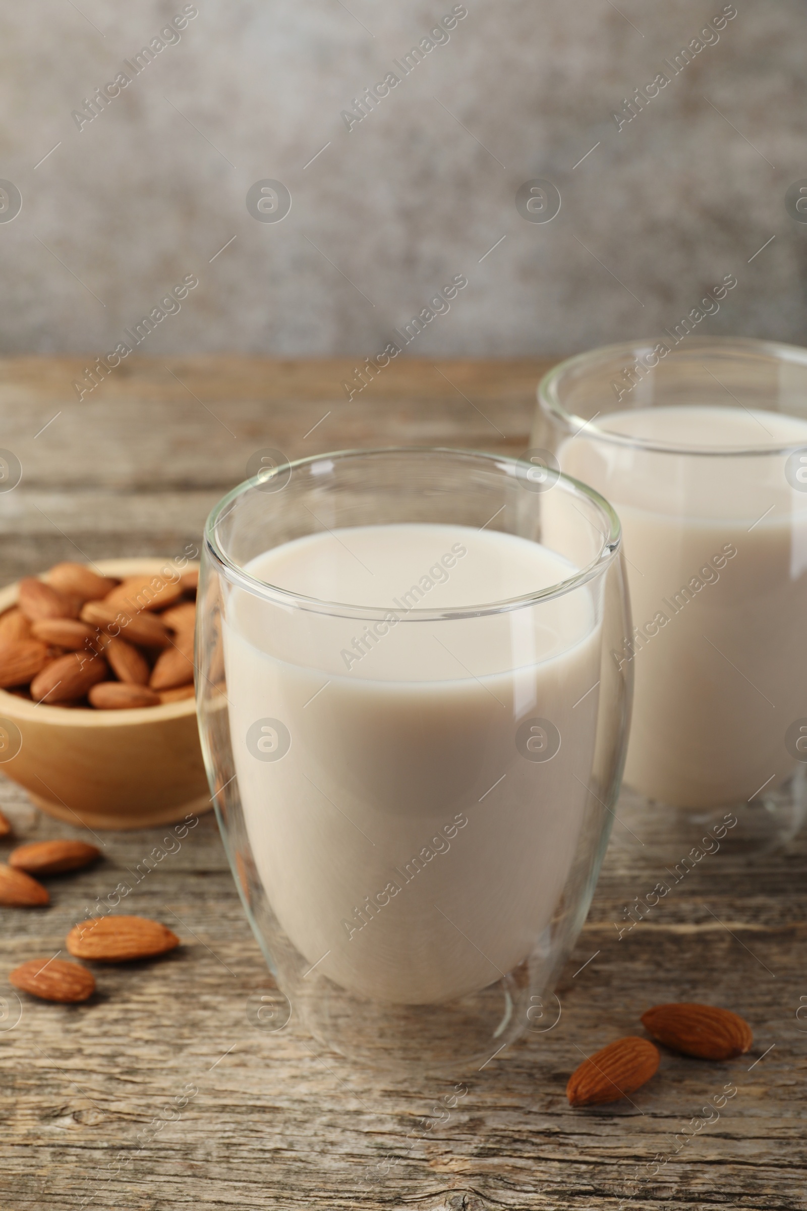 Photo of Fresh nut milk in glasses and almonds on wooden table, closeup