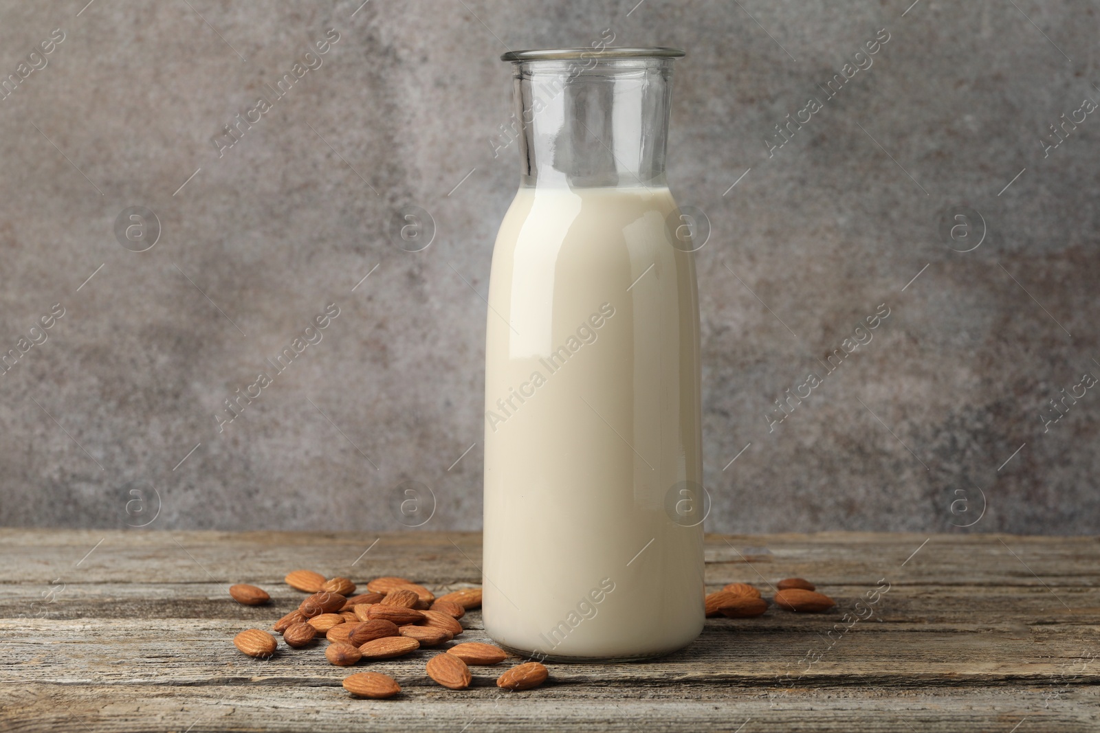 Photo of Fresh nut milk in jug and almonds on wooden table