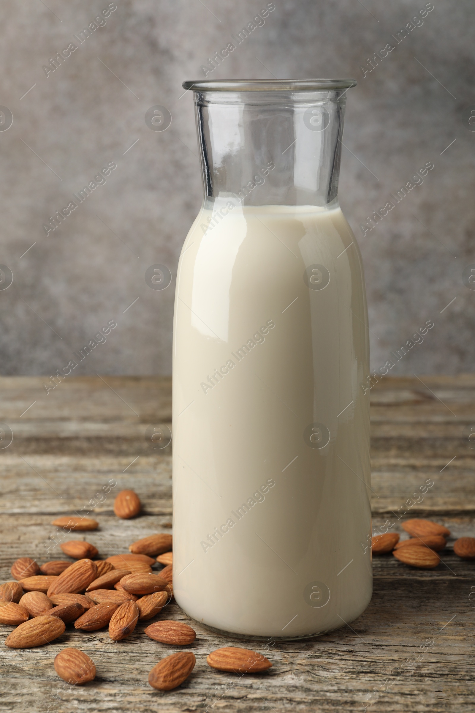 Photo of Fresh nut milk in jug and almonds on wooden table